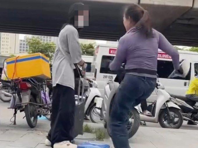 Hình ảnh người phụ nữ bán trà đá (bên phải) đuổi cô gái đứng trên vỉa hè. Ảnh: Cắt từ video