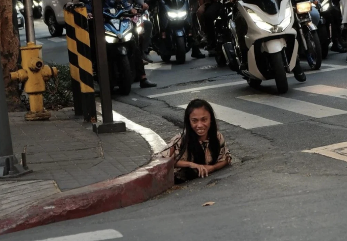 Một phụ nữ được chụp ảnh khi bò ra từ lỗ cống ở Makati, Philippines.