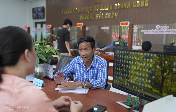 Ông Đinh Đức Duy được chuyên viên Trung tâm phục vụ hành chính công phường Hải Châu hỗ trợ, trao đổi thông tin khi làm thủ tục. Ảnh: Nguyễn Đông