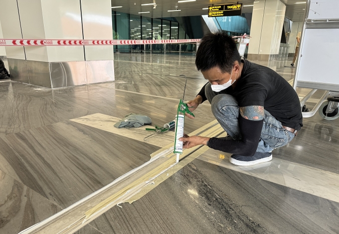 Công nhân của nhà thầu bơm keo hoàn thiện một vị trí khe co giãn trong ga T3, chiều 22/5. Ảnh: Giang Anh