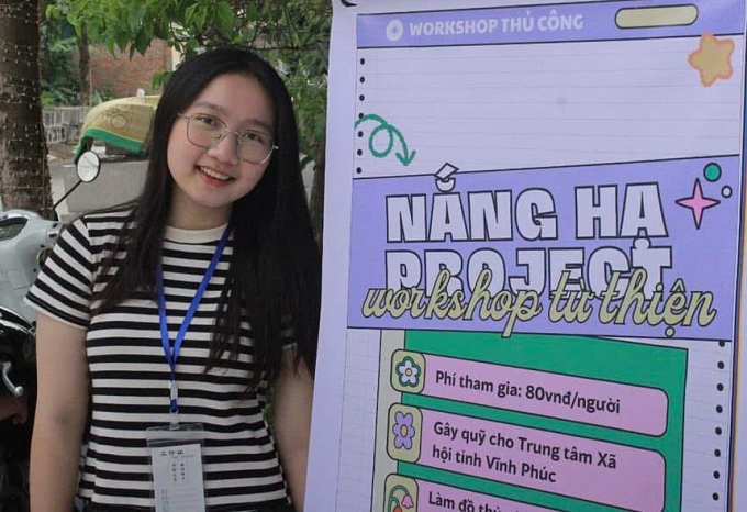 Quỳnh bên standee giới thiệu về workshop Nắng Hạ.